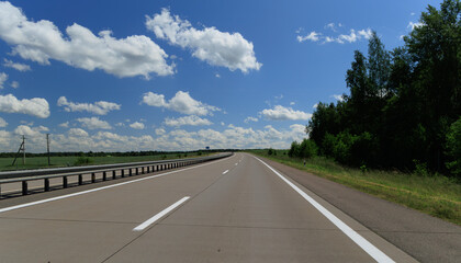 Fototapeta premium Road view on a summer day. Highways and bridge, roadside and white road line markings.