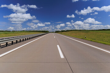 Fototapeta premium Road view on a summer day. Highways and cars, roadside and white road line markings.