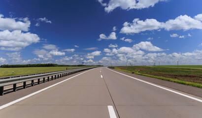 Fototapeta premium Road view on a summer day. Highways and cars, roadside and white road line markings.