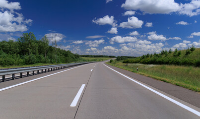 Road view on a summer day. Highways and cars, roadside and white road line markings.