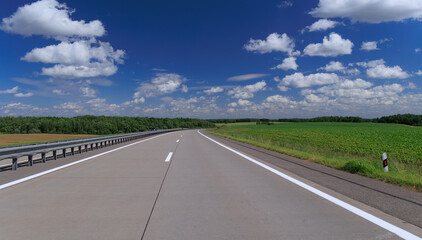 Fototapeta premium Road view on a summer day. Highways and cars, roadside and white road line markings.
