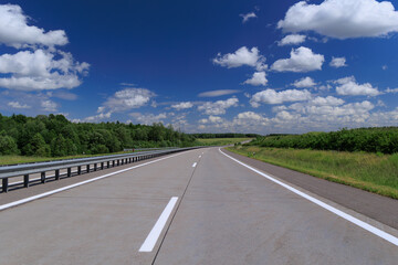 Fototapeta premium Road view on a summer day. Highways and cars, roadside and white road line markings.