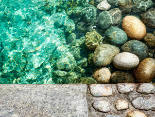Clear water with colorful smooth stones and stone border edge