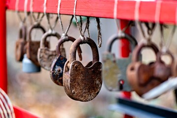 This image shows a collection of old rusted padlocks hanging from a red structure