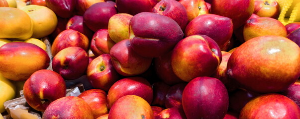 Fresh apples and peaches piled together at a local market showcasing the colorful bounty of late summer harvests in the afternoon sun
