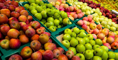 Fresh apples displayed in colorful bins at a bustling market during the afternoon hours in a vibrant urban setting

