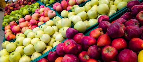 Fresh apples in a vibrant market display showcasing a variety of colors and types during a sunny afternoon
