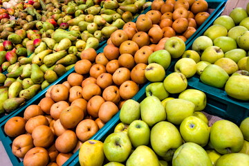Colorful display of fresh apples and pears in a market setting with vibrant green crates in a...
