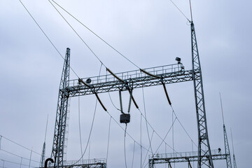High voltage electrical substation infrastructure with transmission lines against a cloudy sky in...