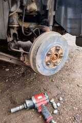 Car brake system repair in a garage with tools scattered on the ground, showcasing the work done on...