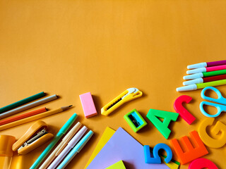 Colorful school supplies arranged on an orange background.