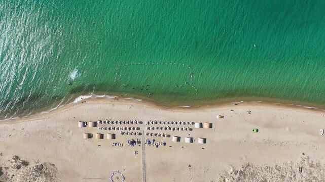4K drone footage of Saros Bay beach in Enez, Edirne, Turkey. Clear turquoise water, aligned sunbeds, umbrellas, and sandy shore create a peaceful summer vibe. Ideal for travel and holiday projects.

