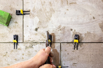 A worker levels freshly laid tiles using a leveling system, ensuring a smooth and professional...