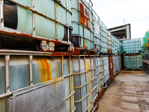 Rusting intermediate bulk containers storage industrial zone depicting logistic and warehouse facility showing transportation of liquid materials for chemical industry and oil industry