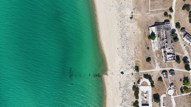 4K aerial drone view of Saros Bay coast in Enez, Edirne, Turkey. Abandoned buildings near the beach, clear turquoise sea, and untouched sandy shore create a unique contrast of nature and history.

