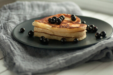 Heart-shaped pancakes topped with blackcurrants on a gray plate