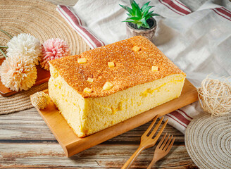 Freshly Baked Golden Cheese Sponge Cake with Cheese Cubes on Top Served on Wooden Board Side view