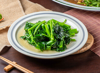 Fresh Stir Fried Chinese Kale with Garlic Sauce on White Plate, Healthy Asian Green Vegetable Side Dish side view