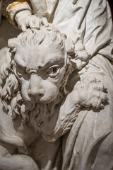 Naklejka premium Sculpture of a small lion at a person’s foot, close-up on the lion’s head. 