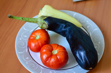 fresh vegetables eggplant two red tomatoes pale yellow bell pepper arranged decorative white plate...