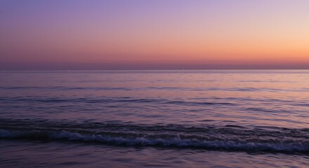 Fototapeta premium Gentle ocean waves at twilight with soft purple and orange hues