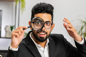 Investigator researcher scientist businessman working at home office holding magnifying glass near...