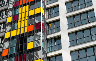 Close up of modern high rise residential tower. Multiple glass windows and balconies form colorful