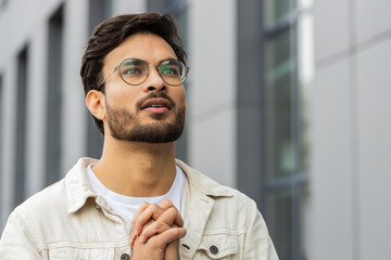 Confident Indian man praying with closed eyes to God asking for blessing, help, forgiveness...