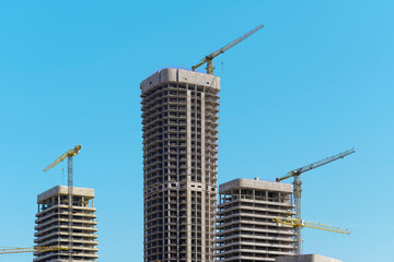 Fototapeta premium Construction of tall multistorey residential tower in developing metropolitan district. Unfinished