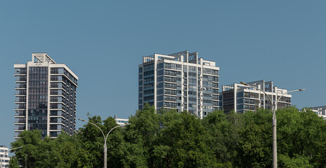 Contemporary highrise condominium with glass facade set against a blue cityscape skyline. Surrounded