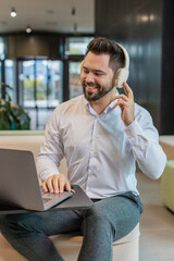 Happy overjoyed Caucasian bearded businessman sitting in modern office lobby listening to energetic...