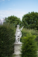 Fototapeta premium statue in the park, elegant white stone or marble statue positioned on a pedestal within the formal gardens of the Belvedere Palace. The sculpture depicts a classical or allegorical figure