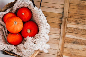 Bright orange pumpkins in a cozy basket on a wooden floor during autumn season