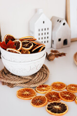 Decorative bowl filled with dried orange slices near ceramic houses on a table