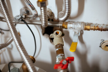 A close-up reveals a complex network of interconnected metal pipes, brass fittings, and valves,...