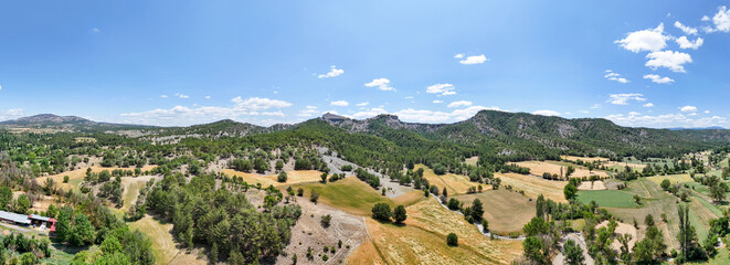Aerial panoramic view of Asarlık Hills in Nallıhan, Turkey. The scene features forested hills, meadows, rural roads, and scattered trees under a clear blue sky. Ideal for nature and countryside themes