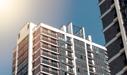 Sunny afternoon view of tall glass skyscraper with modern facade and balconies in downtown city.