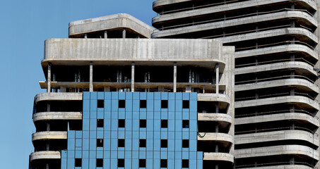 Tall modern building under construction with concrete structure, glass windows, and balconies in