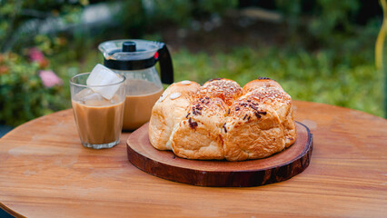 Medium Close up, Fresh bread served with hot coffee on a table, with blurred plants in the background for a cozy breakfast atmosphere.