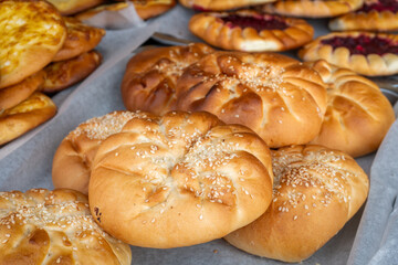 Freshly baked sesame rolls on a large tray