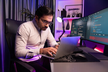 Smart IT developer working on laptop to type searching in software coding system at neon light...