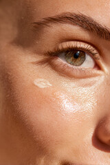 Close-up of radiant face with skincare product application for hydration and healthy skin promotion.