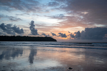 A stunning monsoon sunset at Miramar Beach in Panjim, Goa, featuring the Arabian Sea, rocky cliff,...