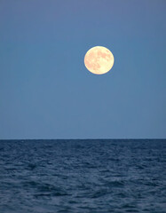 Full moon over ocean at twilight