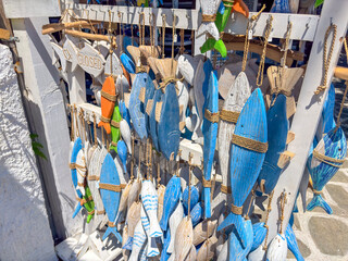 Colorful wooden fish decorations in shades of blue and white hanging outside a souvenir shop in a...