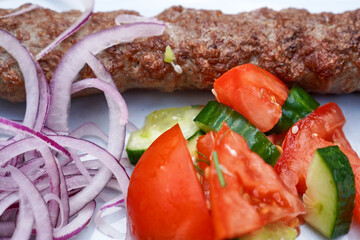Kebab with vegetables and pickled onions on a gray plate