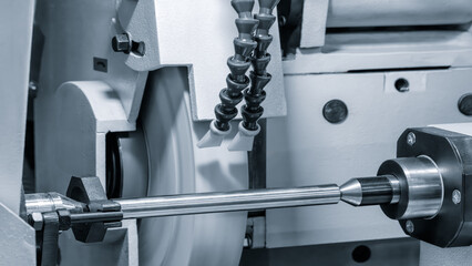 Industrial sharpening machine with large abrasive white disc close-up sharpening round metal part, industrial conceptual background