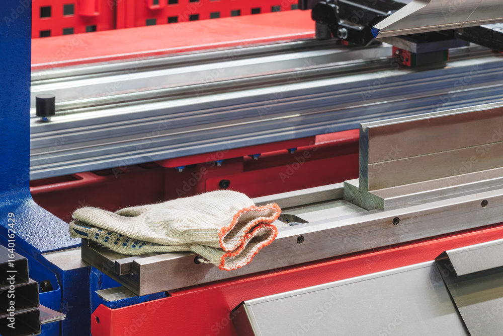 Poster metal pieces are being cut by machine. pieces all same size and shape, and they are arranged in a ro