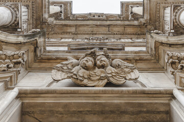 View of ornate stone carvings of cherubic figures and architectural details create a textured, historical facade, Sulmona, Abruzzo, Italy.