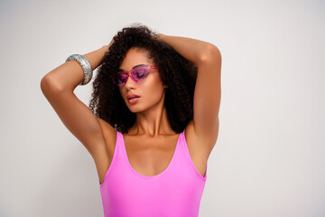 Trendy woman posing confidently in vibrant pink swimwear and trendy sunglass against a minimalistic...